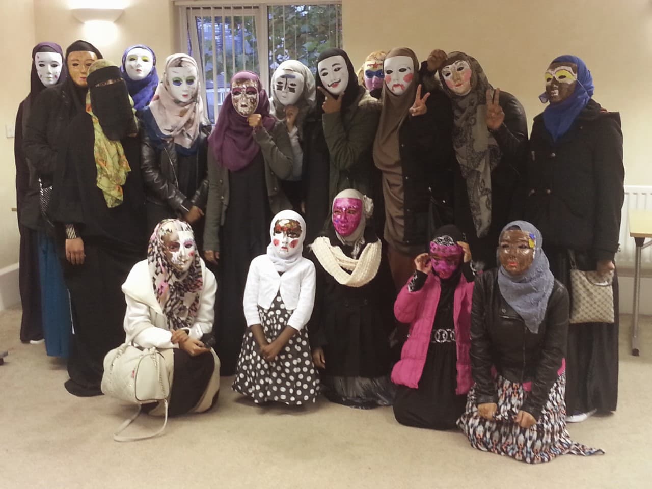 Women and girls showing decorated masks they made at a BSCA community arts session