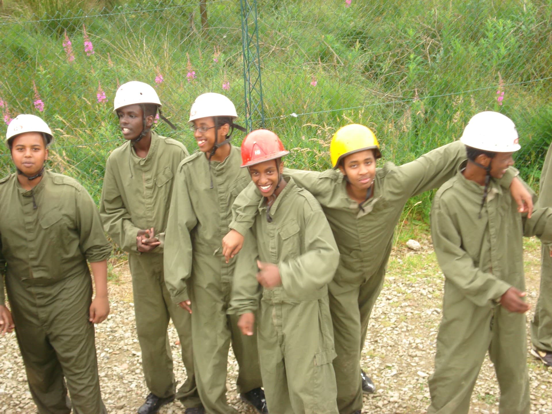 Young people in overalls and safety helmets enjoying an outdoor activity day